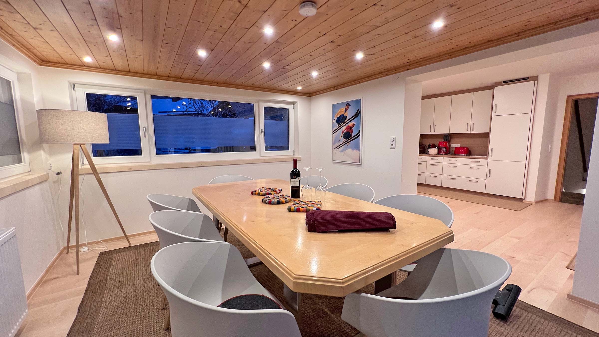 Langer Esstisch mit weißen Schalenstühlen unter der Holzdecke