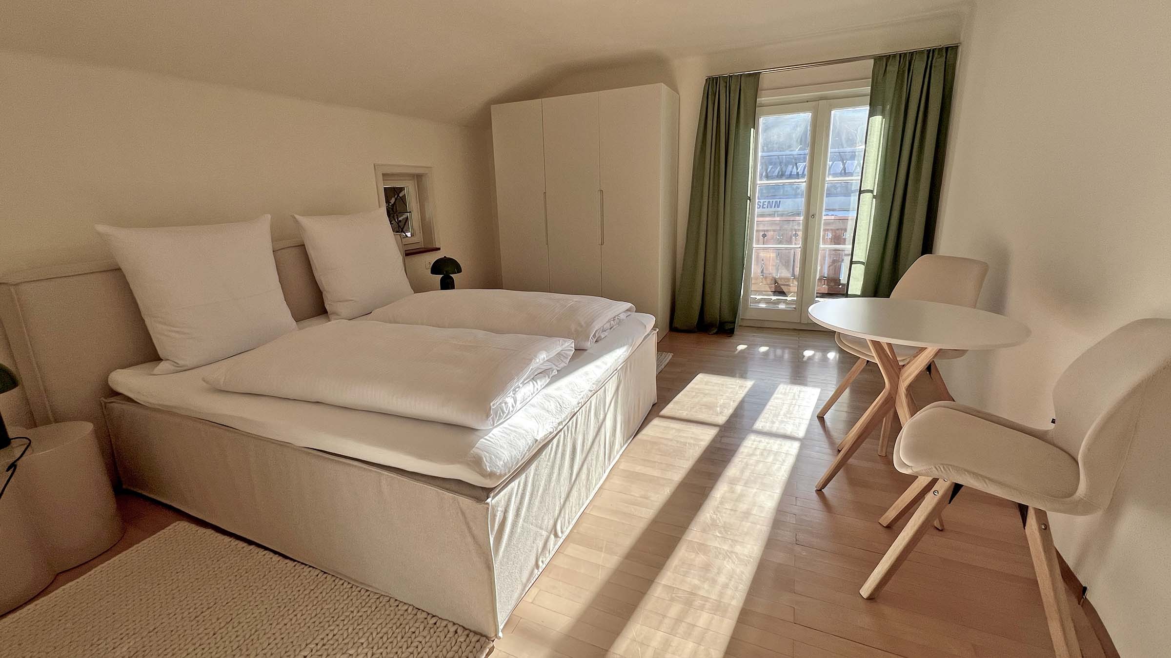 Schlafzimmer 1 mit Doppelbett, Tisch und Stühlen an der Balkontür