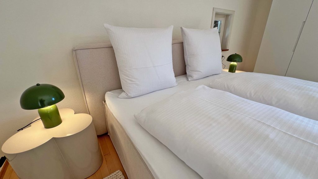 Frisch bezogenes Doppelbett mit Nachttischlampe