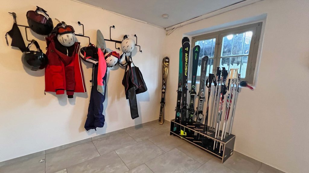 Skiraum mit Haken für Helme und Jacken, daneben ein Skiständer