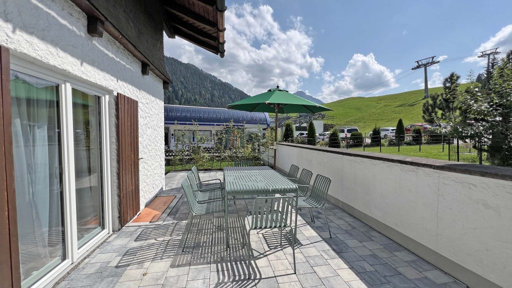 Terrasse mit langem Tisch und Blick auf die Wiese