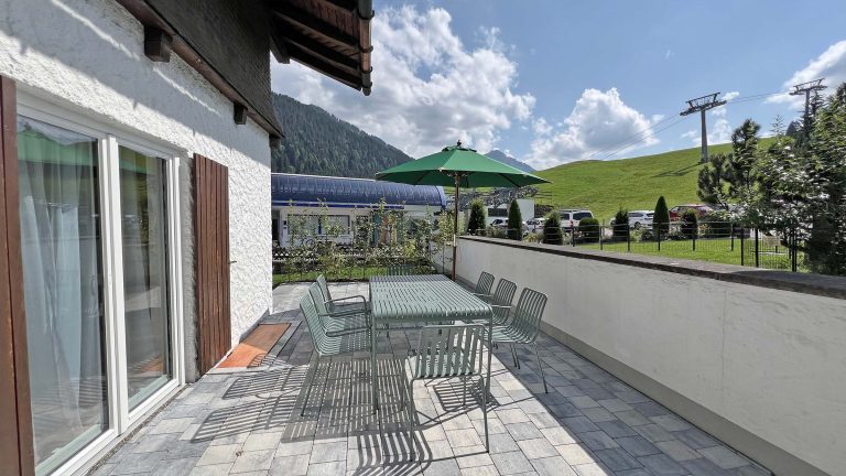Terrasse mit langem Tisch und Blick auf die Wiese