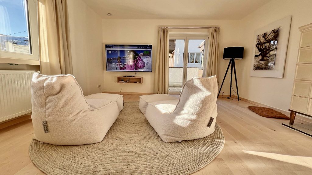 Wohnzimmer mit Fernseher, Sitzsäcken und rundem Teppich